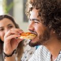 homem feliz comendo pizza