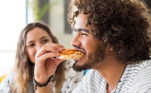 homem feliz comendo pizza