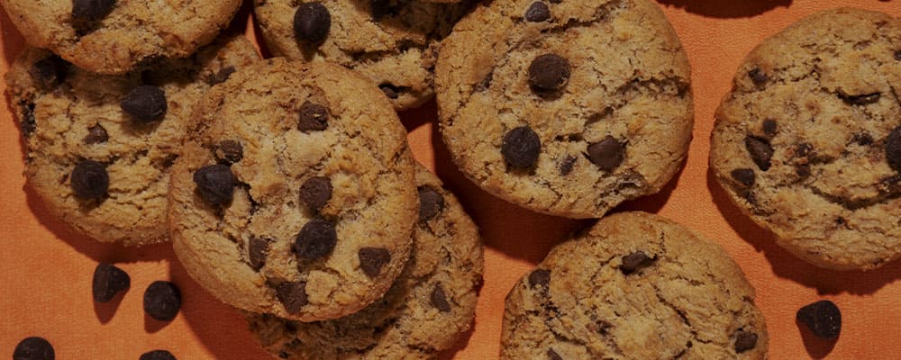 Cookies de chocolate sobre uma superfície laranja.