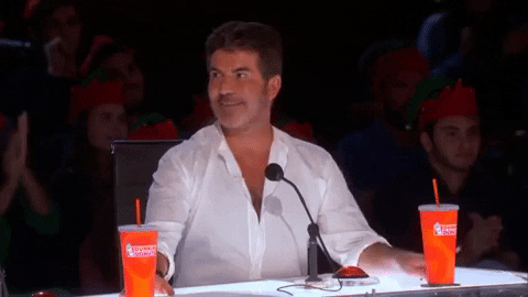 Simon Cowell aplaudindo alguém no palco do programa The X Factor.