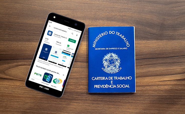Celular com o app da Carteira de Trabalho Digital aberto e ao lado está a versão impressa do documento.