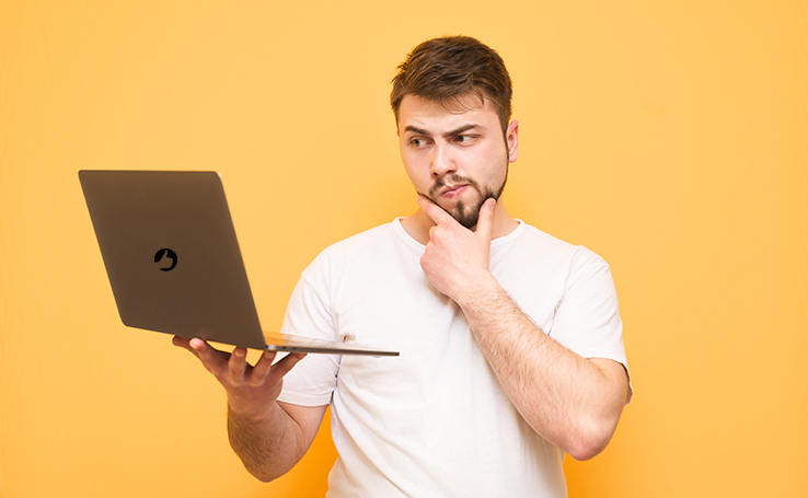 Homem segurando um notebook Positivo com a mão no queixo em sinal de dúvida.