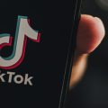 mão segurando um celular com o app do TikTok aberto