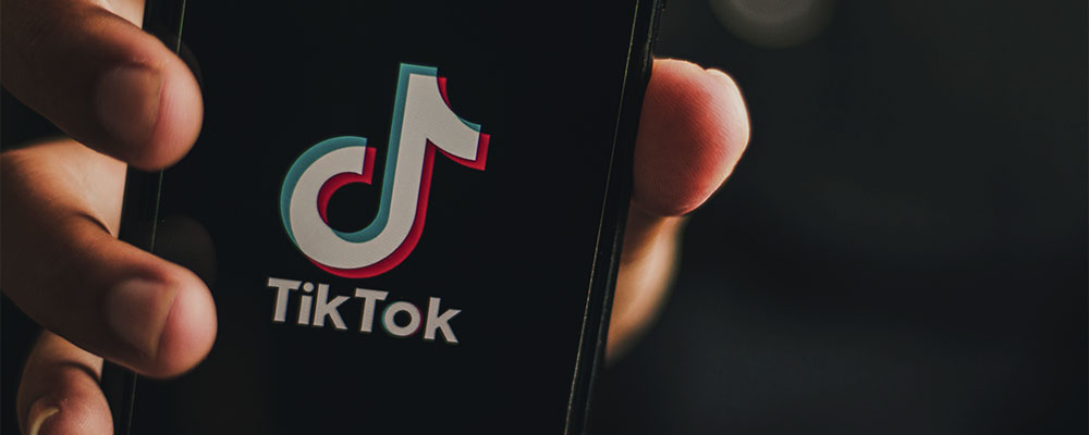 mão segurando um celular com o app do TikTok aberto