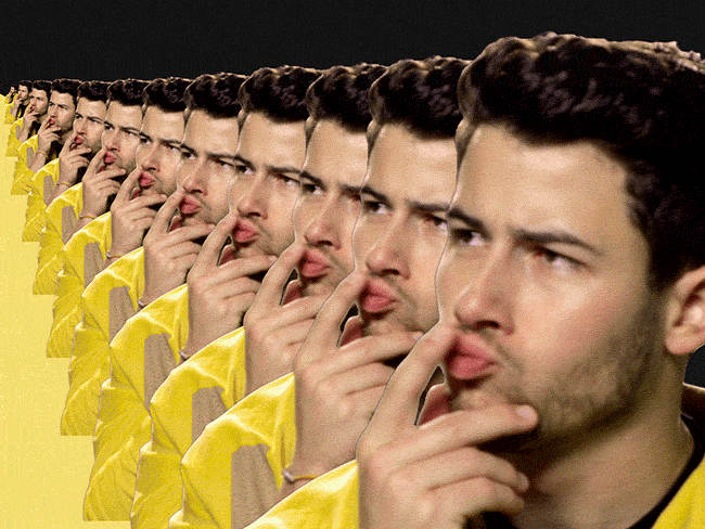 Nick Jonas batendo o dedo indicador no lábio indicando dúvida.