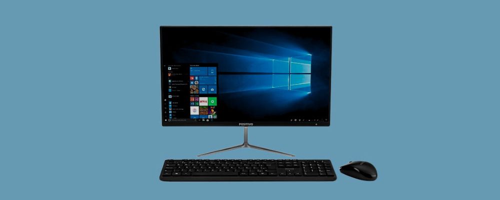 Computador em cima da mesa com a área de trabalho do Windows 10 e o Menu Iniciar aberto.