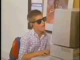 Garoto de óculos de sol usando um computador muito antigo e dançando ao mesmo tempo.