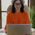 mulher em um escritório sorrindo e escrevendo em um notebook