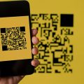 celular apontando para um QR Code com um fundo amarelo