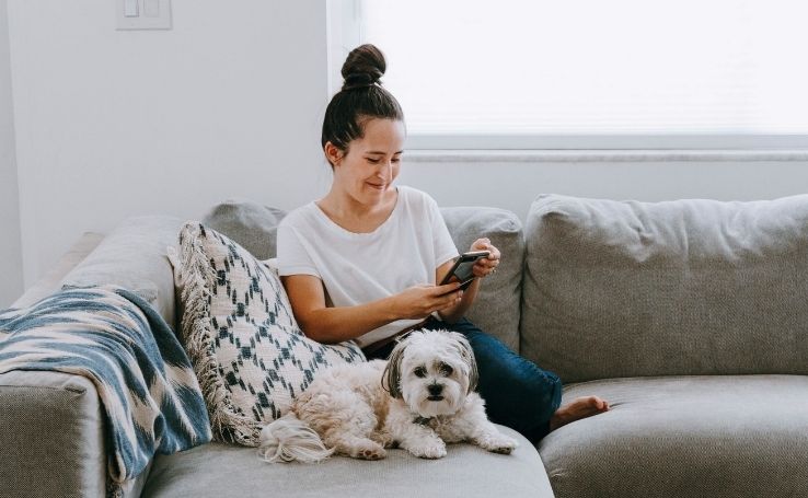 garota-sentada-no-sofa-com-cachorro-usando-celular