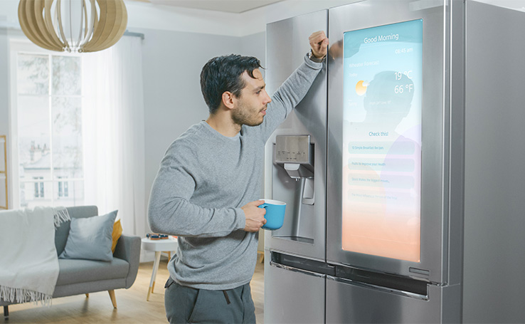 homem bebendo café em frente à uma geladeira smart, uma das tecnologias indispensáveis