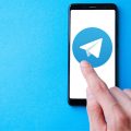 homem usando telegram no celular com fundo azul