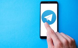 homem usando telegram no celular com fundo azul