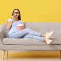 mulher assistindo os lançamentos da Netflix e comendo pipoca