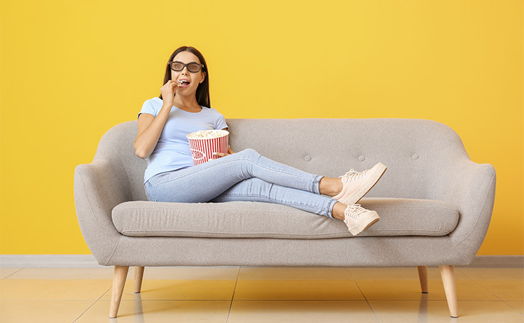 mulher assistindo os lançamentos da Netflix e comendo pipoca