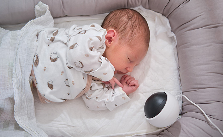 bebê com uma câmera de monitoramento no berço, um dos eletrônicos que pais deveriam ter