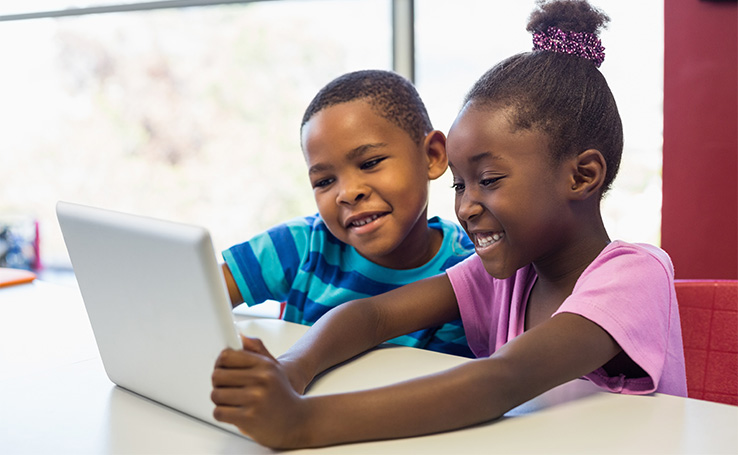duas crianças brincando com um tablet infantil, um dos eletrônicos que ajudam na rotina dos pais