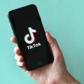 mão segurando um celular com o logo do TikTok aparecendo na tela