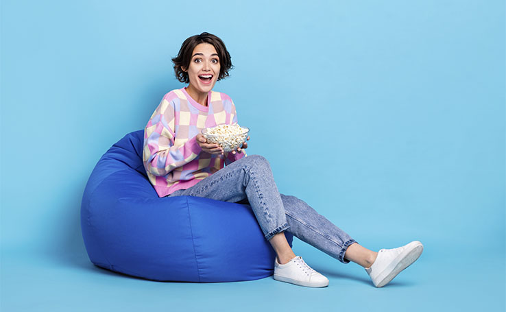garota sentada em um puff com uma tigela de pipoca assistindo os lançamentos de setembro da Netflix