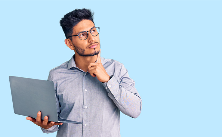 homem segurando um notebook com o dedo no queixo indicando dúvida