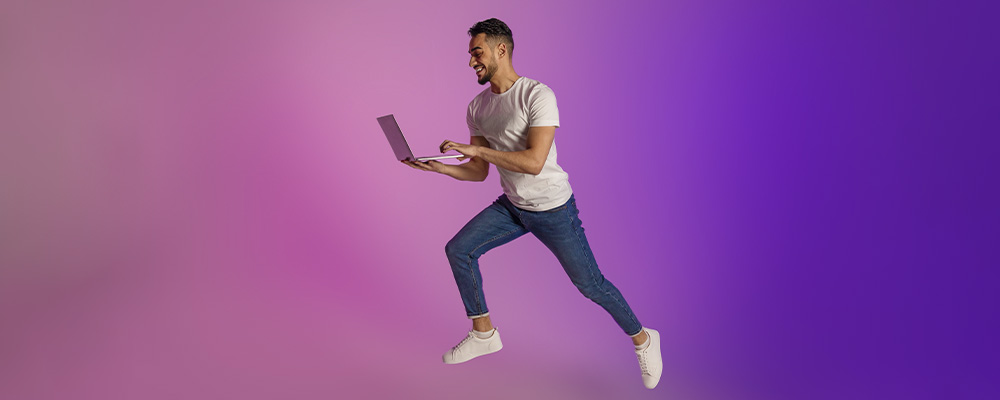 rapaz utilizando um notebook em um fundo rosa e roxo