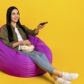 garota sentada em um pufe segurando uma vasilha de pipoca enquanto assiste aos lançamentos da Netflix