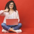 garota usando notebook em um fundo vermelho