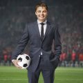homem de terno e gravata segurando uma bola de futebol, representando o jogo Football Manager