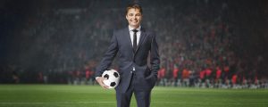 homem de terno e gravata segurando uma bola de futebol, representando o jogo Football Manager