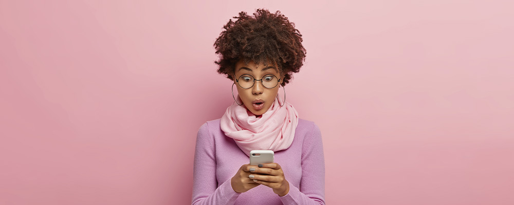 menina usando celular com uma expressão de surpresa