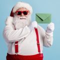 Papai Noel de óculos escuros segurando uma cartinha