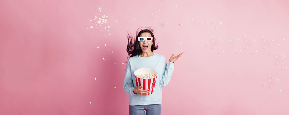 garota com óculos 3D e segurando um balde de pipoca, pronta para assistir aos filmaços que acabaram de chegar à Netflix