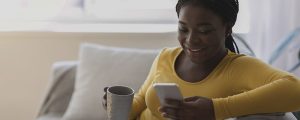 mulher sentada no sofá bebendo café enquanto usa o recurso de Notas do Instagram