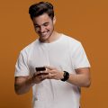 homem sorrindo e mecheno em seu celular