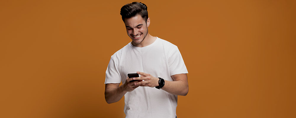 homem sorrindo e mecheno em seu celular