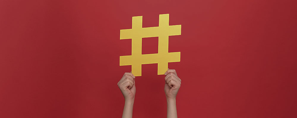 pessoa segurando uma hashtag amarela sobre um fundo vermelho