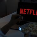 pessoa assistindo Netflix pelo notebook enquanto come pipoca
