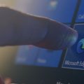 dedo apontando para o ícone do Microsoft Edge na tela de um computador