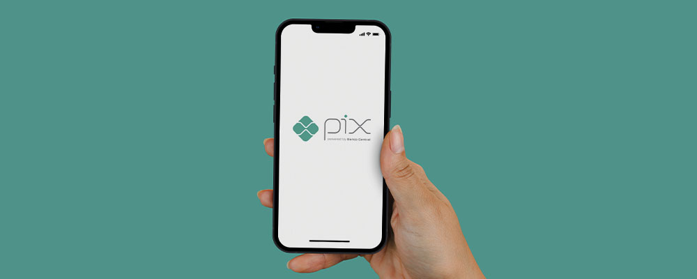 mulher segurando um celular com o logo do Pix