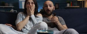 casal assustando assistindo filme na Netflix enquanto come pipoca no sofá