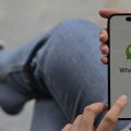 mulher sentada de pernas cruzadas com o WhatsApp aberto no celular