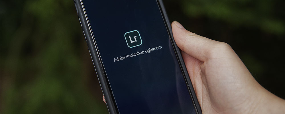 pessoa segurando um celular com o app Lightroom Mobile aberto