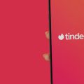 mulher segurando um celular com o app do Tinder aberto