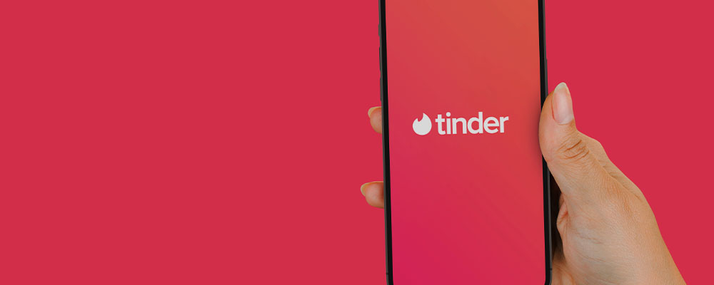 mulher segurando um celular com o app do Tinder aberto