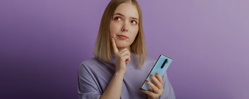 garota com dúvidas segurando um smartphone