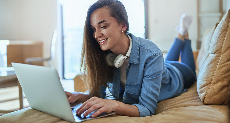 mulher deitada no sofá usando um notebook