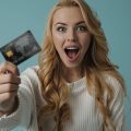 mulher supresa segurando um cartão de crédito
