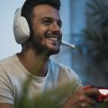 homem de headphones segurando um controle de videogame, pois está jogando jogos online
