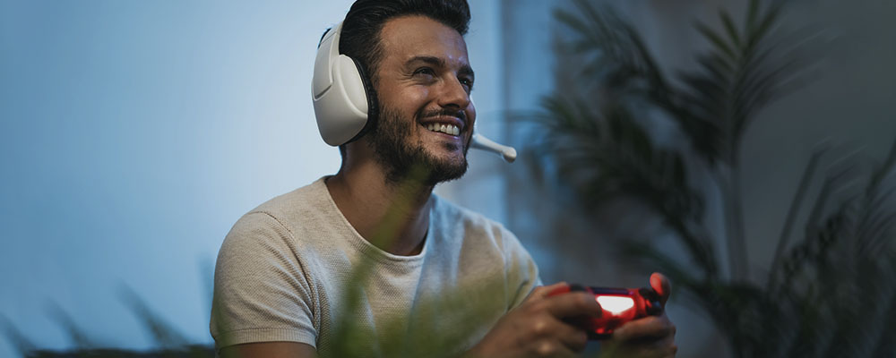 homem de headphones segurando um controle de videogame, pois está jogando jogos online