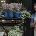microempresário na porta de sua floricultura consultando dados de sua MEI pelo celular